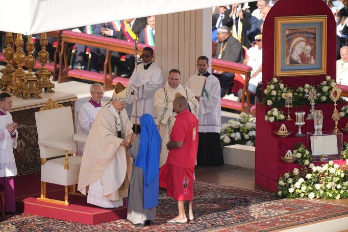 Věřící přinášejí obětiny papeži Lvu XIV. k oltáři, kde pod ikonou Panny Marie z Apokalypsy se svatými a anděly spočívají relikvie sedmi nových katolických svatých.