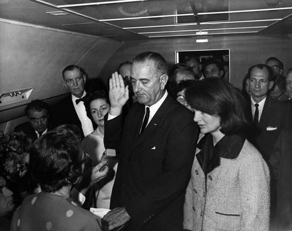 Lyndon B. Johnson skládá prezidentskou přísahu na palubě Air Force One pár hodin po atentátu na Kennedyho. Vpravo Jackie Kennedyová. 22. listopadu 1963.