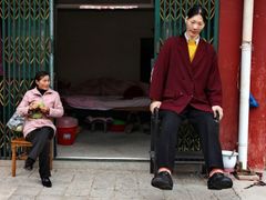 Nejvyšší žena světa, Číňanka Jao Te-fen měří 236 cm. Na snímku s kamarádkou sedí před svým domem.