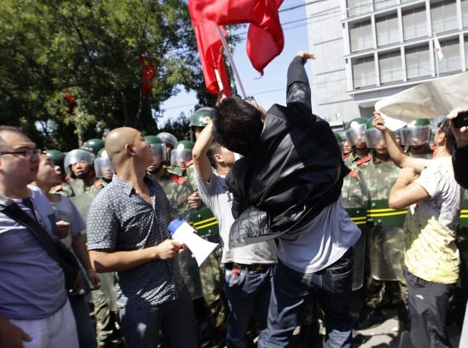 protester uses a megaphone to shout slogans during a protest outside the Japanese embassy (in the background) in Beijing September 15, 2012. Thousands of protesters besieged the Japanese embassy in Beijing on Saturday, hurling rocks and bottles at the building as police struggled to keep control, amid growing tensions between Asia's two biggest economies over a group of disputed islands. REUTERS/Jason Lee (CHINA - Tags: CIVIL UNREST POLITICS)