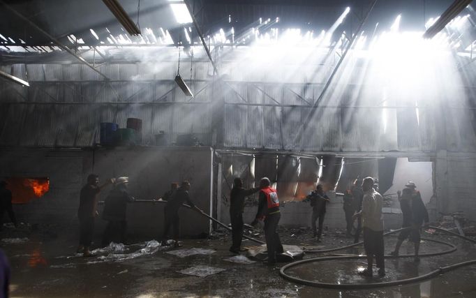 Firefighters try to extinguish a fire at a factory, which according to Palestinians was hit by an Israeli air strike in Gaza November 16, 2012. Egyptian Prime Minister Hisham Kandil, on a brief visit to the Gaza Strip on Friday, denounced Israel's attacks on the Palestinian territory and said Cairo would try to secure a ceasefire. Fighting continued along the Israel-Gaza border during Kandil's three-hour visit. REUTERS/Ahmed Zakot (GAZA - Tags: CIVIL UNREST MILITARY POLITICS TPX IMAGES OF THE DAY) Published: Lis. 16, 2012, 9:25 dop.