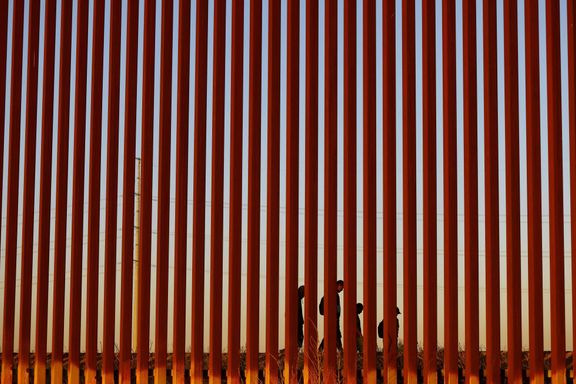 Migranti, kteří se snaží dostat do Spojených států, procházejí kolem hraniční zdi v Ciudad Juarez v Mexiku, pohled z El Pasa v Texasu.