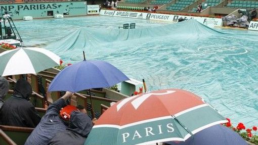 Diváci se schovávají pod deštníky v průběhu nedělního programu grandslamového French Open.
