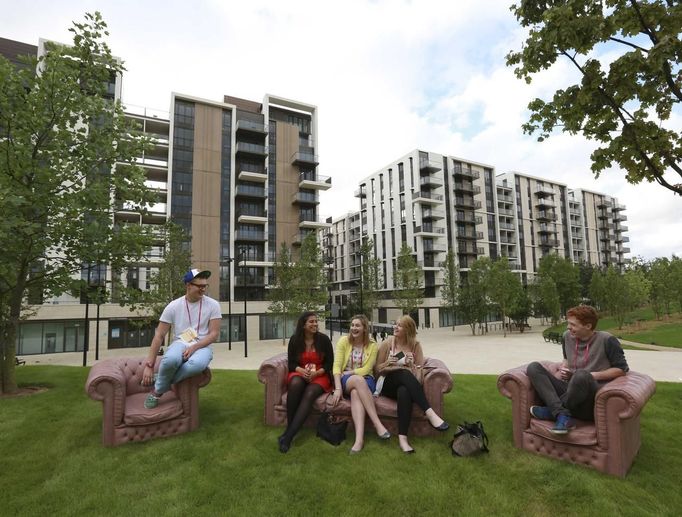 Students who were asked to test facilities for the night sit in Victory Park in the Olympic Village built for the London 2012 Olympic Games in Stratford, east London June 29, 2012. The village will accomodate up to 16,000 athletes and officials from more than 200 nations. Picture taken June 29, 2012. REUTERS/Olivia Harris (BRITAIN - Tags: BUSINESS CONSTRUCTION SPORT OLYMPICS CITYSPACE) Published: Čer. 30, 2012, 11:59 dop.