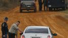 As bomb squad personnel (in back) prepare to enter the scene, law enforcement officials turn back a vehicle at a roadblock near a standoff with the shooter in Midland City, Alabama January 30, 2013. A standoff continued on Wednesday with a gunman who boarded an Alabama school bus and fatally shot the driver before fleeing with a young child and holing up in an underground bunker, authorities said. REUTERS/Phil Sears (UNITED STATES - Tags: CRIME LAW) Published: Led. 30, 2013, 7:05 odp.