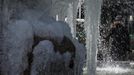 A woman takes a picture of a fountain partially covered by ice at Bryant Park in New York, January 24, 2013. Frigid arctic air held the U.S. Midwest and Northeast in its icy grip on Wednesday, with the cold so dangerous that municipal emergency warming centers opened up and ski resorts shut down. Wintry conditions from Minneapolis to Washington marked the coldest conditions in many parts of the United States in four years, but were nowhere near the record lows for January, meteorologists said. REUTERS/Eduardo Munoz (UNITED STATES - Tags: ENVIRONMENT SOCIETY) Published: Led. 24, 2013, 6:54 odp.