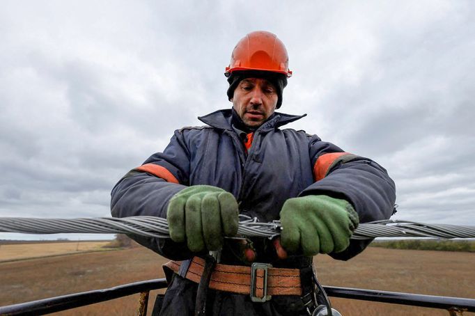 Elektrikář opravuje vedení nedaleko Charkova. Velká většina Ukrajiny už svítí, dodávky elektřiny jsou stabilní.