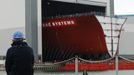 A worker watches as the forward section of the aircraft carrier HMS Queen Elizabeth is moved onto a barge at HM Naval Base in Portsmouth, southern England May 14, 2012. The hull will be transported by a sea going barge to Rosyth in Scotland where the ship will be assembled in dry dock. REUTERS/Luke MacGregor (BRITAIN - Tags: BUSINESS EMPLOYMENT MILITARY) Published: Kvě. 14, 2012, 3:39 odp.