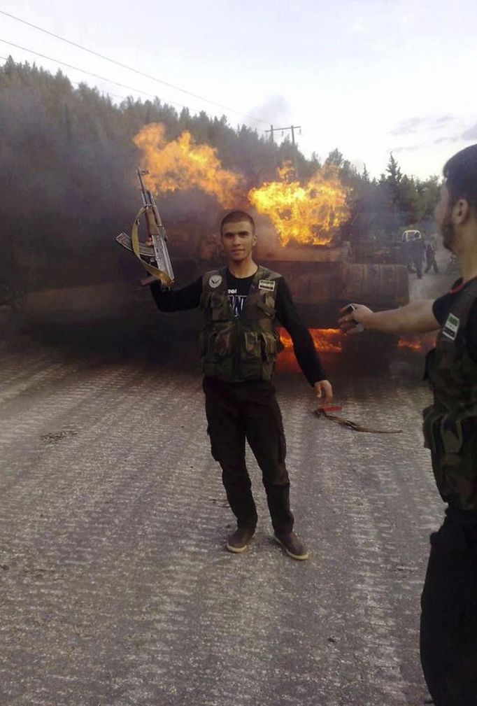 Rebel fighter Mahmoud Al-Ghandour, whom opposition say was killed while fighting with forces loyal to Syria's President Bashar al-Assad, poses in front of a burning tank near Aleppo, in this undated handout photo received on July 29, 2012. REUTERS/Shaam News Network/Handout (SYRIA - Tags: POLITICS CIVIL UNREST MILITARY) FOR EDITORIAL USE ONLY. NOT FOR SALE FOR MARKETING OR ADVERTISING CAMPAIGNS Published: Čec. 29, 2012, 9:46 odp.