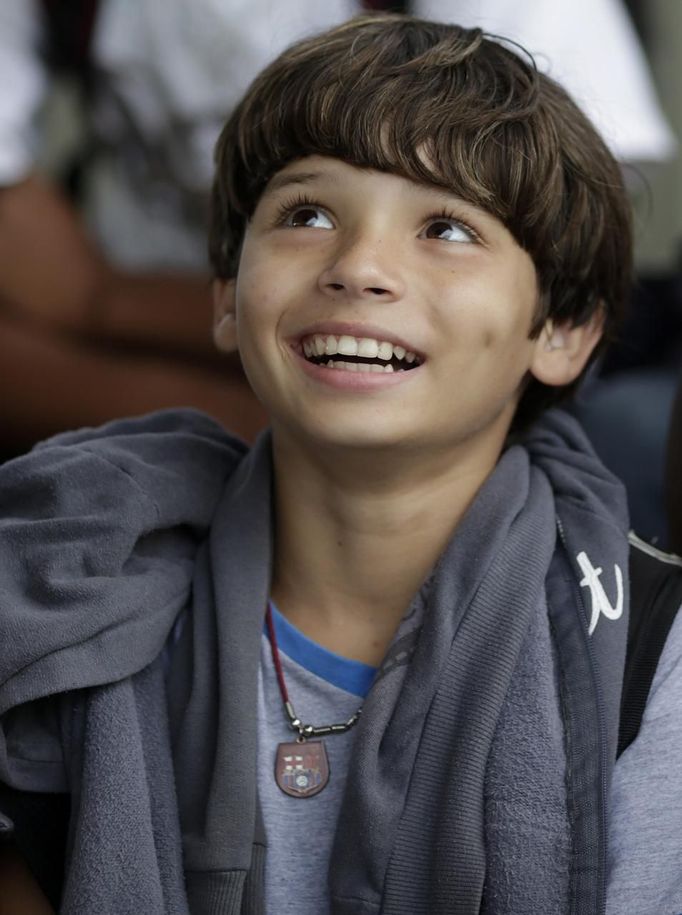 Gabriel Muniz, 11, wearing a Barcelona FC necklace, smiles in Campos dos Goytacazes, 274 kilometres (170 miles) northeast of Rio de Janeiro August 23, 2012. Despite being born with malformation of his feet, fourth grader Gabriel puts in hours into soccer everyday in his neighbourhood. He aspires to be a professional soccer player just like his idol Argentina's Lionel Messi of Barcelona FC. REUTERS/Ricardo Moraes (BRAZIL - Tags: SPORT SOCCER SOCIETY HEALTH) Published: Srp. 24, 2012, 2:25 dop.