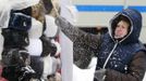 A shop assistant removes snow from Russian traditional hats, also known as Ushanka hats, near Red Square during heavy snowfall in central Moscow, November 29, 2012. REUTERS/Sergei Karpukhin (RUSSIA - Tags: ENVIRONMENT SOCIETY) Published: Lis. 29, 2012, 11:31 dop.