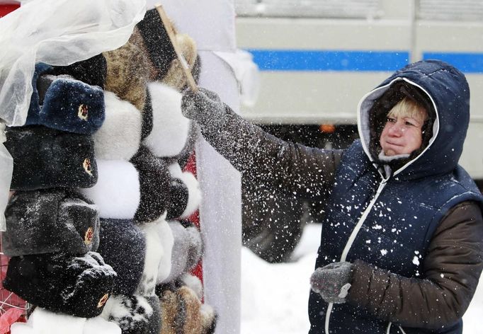 A shop assistant removes snow from Russian traditional hats, also known as Ushanka hats, near Red Square during heavy snowfall in central Moscow, November 29, 2012. REUTERS/Sergei Karpukhin (RUSSIA - Tags: ENVIRONMENT SOCIETY) Published: Lis. 29, 2012, 11:31 dop.