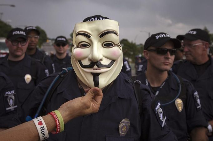 A demonstrator holds a Guy Fawkes mask in front of a line of police officers blocking a protest march near the site of the Democratic National Convention in Charlotte, North Carolina on September 4, 2012. President Barack Obama will be nominated as the Democratic candidate at the convention, along with Vice President Joe Biden as his running mate, for November's U.S. presidential election. REUTERS/Adrees Latif (UNITED STATES - Tags: POLITICS ELECTIONS CIVIL UNREST TPX IMAGES OF THE DAY) Published: Zář. 4, 2012, 10:05 odp.