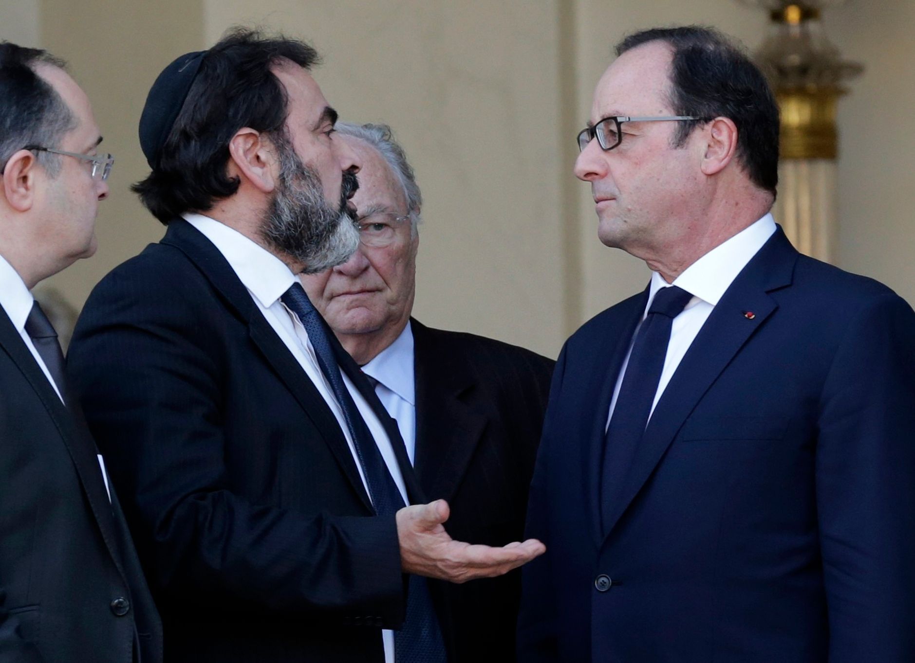 French President Francois Hollande speaks with Jewish central Consistory President Joel Mergui as Roger Cukierman, President of the Representative Council of France's Jewish Associations (CRIF) stands