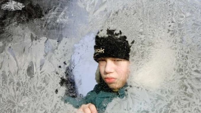 Běloruský chlapec za zamrzlým oknem autobusu v Minsku