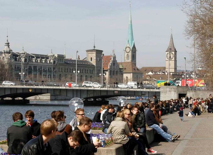 Lidé relaxují u řeky Limmat, která vytéká z Curyšského jezera a dělí Staré město Curych na dvě části.