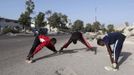 Somali athletes stretch along a street as they train during preparations for the 2012 London Olympic Games in Somalia's capital Mogadishu in this March 14, 2012 file photo. Training in a bullet-riddled stadium where the remains of a rocket propelled grenade lies discarded on the track's edge counts as progress for Somali Olympic hopeful Mohamed Hassan Mohamed. A year ago, Mogadishu's Konis stadium was a base for Islamist militants and a work out meant at times running through the streets, dodging gun-fire and mortar shells in one of the world's most dangerous cities. Picture taken March 14, 2012. To match OLY-SOMALIA-HOPES/ REUTERS/Feisal Omar/Files (SOMALIA - Tags: SPORT ATHLETICS SOCIETY OLYMPICS) Published: Čer. 11, 2012, 7:10 dop.