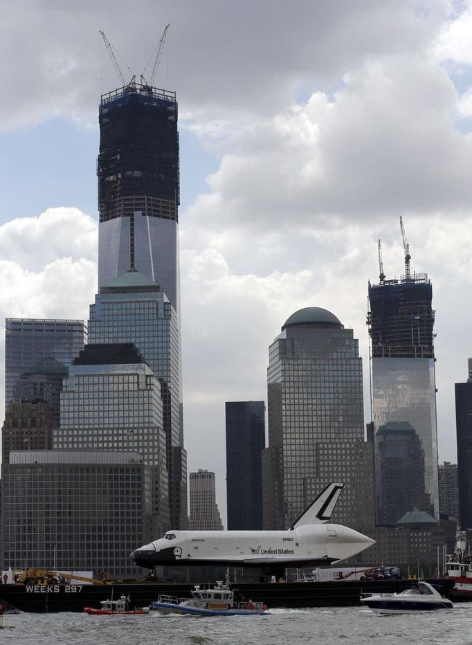 The Space Shuttle Enterprise, passes lower Manhattan and the still under construction 1 World Trade Center tower (C) as it rides on a barge in New York harbor, June 6, 2012. The Space Shuttle Enterprise was being moved up the Hudson River to be placed at the Intrepid Sea, Air and Space Museum. REUTERS/Mike Segar (UNITED STATES - Tags: TRANSPORT SCIENCE TECHNOLOGY) Published: Čer. 6, 2012, 6:09 odp.