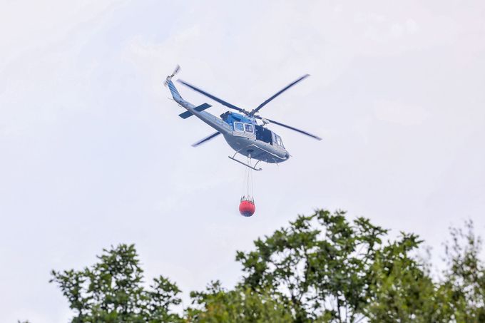 Policejní vrtulník během hašení požáru v Národním parku České Švýcarsko. 26. 7. 2022