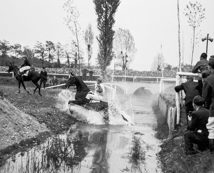 Jezdec s koněm padá do vodního příkopu během 64. ročníku Velké pardubické steeplechase na závodišti v Pardubicích, 18. října 1953.