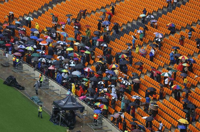 People carry umbrellas as they arrive ahead of former South African President Nelson Mandela's national memorial service at the First National Bank (FNB) Stadium, also known as Soccer City, in Johannesburg December 10, 2013.