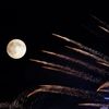 Fireworks streak past in front of the supermoon outside the town of Mosta