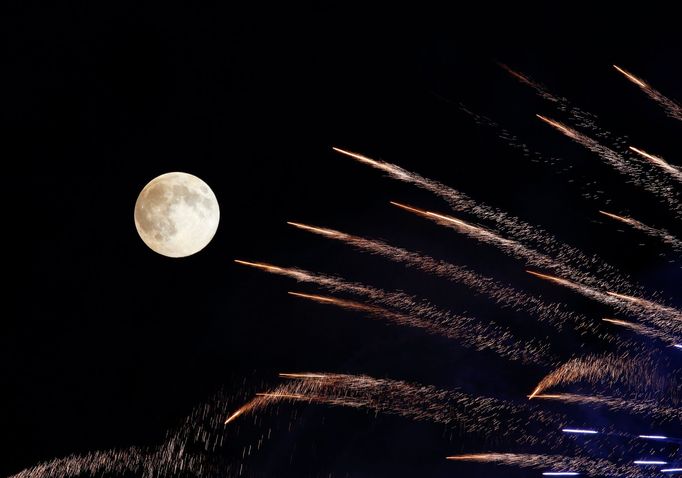 Fireworks streak past in front of the supermoon outside the town of Mosta, celebrating the feast of its patron saint, in central Malta