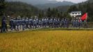 Mid-level government officials dressed in red army uniforms walk next to a rice field as they visit an old house where former Chinese leader Mao Zedong used to live, during a five-day training course at the communist party school called China Executive Leadership Academy of Jinggangshan, in Jiangxi province September 21, 2012. China Executive Leadership Academy was established in 2005 by the Central Committee of the Communist Party of China, after the 16th Communist Party Congress in 2002. By the end of August 2012, the academy has held 789 training classes for almost 40,000 people. During the course, trainees listen and sing revolutionary songs, visit old revolutionary sites and review historical communist materials. China has yet to announce the starting date for the 18th Communist Party Congress, China's biggest political meeting in a decade, which will see the transfer of power from President Hu Jintao and Premier Wen Jiabao to a new generation. REUTERS/Carlos Barria (CHINA - Tags: POLITICS SOCIETY) Published: Zář. 21, 2012, 3:46 odp.