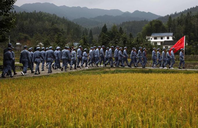 Mid-level government officials dressed in red army uniforms walk next to a rice field as they visit an old house where former Chinese leader Mao Zedong used to live, during a five-day training course at the communist party school called China Executive Leadership Academy of Jinggangshan, in Jiangxi province September 21, 2012. China Executive Leadership Academy was established in 2005 by the Central Committee of the Communist Party of China, after the 16th Communist Party Congress in 2002. By the end of August 2012, the academy has held 789 training classes for almost 40,000 people. During the course, trainees listen and sing revolutionary songs, visit old revolutionary sites and review historical communist materials. China has yet to announce the starting date for the 18th Communist Party Congress, China's biggest political meeting in a decade, which will see the transfer of power from President Hu Jintao and Premier Wen Jiabao to a new generation. REUTERS/Carlos Barria (CHINA - Tags: POLITICS SOCIETY) Published: Zář. 21, 2012, 3:46 odp.