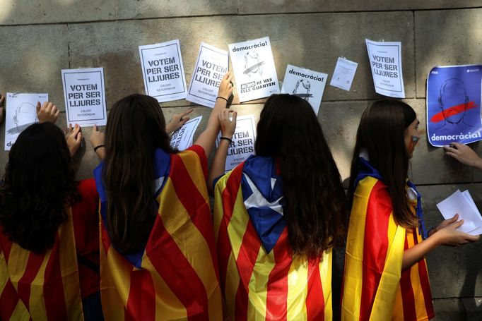 Dívky, oblečené do katalánských separatistických vlajek, během demonstrace v Barceloně lepí na zeď plakáty na podporu referenda o nezávislosti, které bude příští víkend.