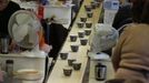 Newly decorated cups move along a conveyor belt after being covered in tissue paper transfers in a workshop at the Middleport pottery in Stoke-on-Trent, central England January 22, 2013. The pottery which dates back to 1888 and was rescued from closure in 2009, continues to use traditional methods to produce its range of ceramics and famous Burleigh Ware pottery. REUTERS/Phil Noble (BRITAIN - Tags: BUSINESS EMPLOYMENT SOCIETY) Published: Led. 22, 2013, 4:36 odp.