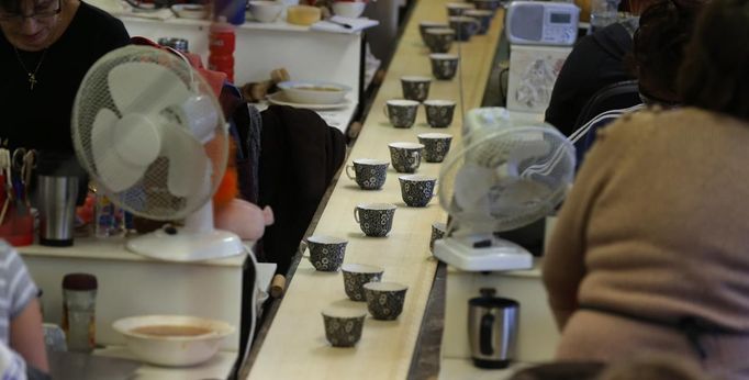 Newly decorated cups move along a conveyor belt after being covered in tissue paper transfers in a workshop at the Middleport pottery in Stoke-on-Trent, central England January 22, 2013. The pottery which dates back to 1888 and was rescued from closure in 2009, continues to use traditional methods to produce its range of ceramics and famous Burleigh Ware pottery. REUTERS/Phil Noble (BRITAIN - Tags: BUSINESS EMPLOYMENT SOCIETY) Published: Led. 22, 2013, 4:36 odp.