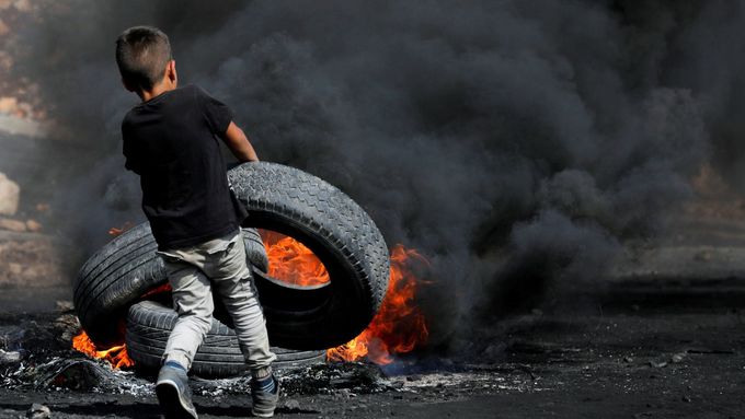 Nejsilnější fotky roku z protestů: Chlapec zapaluje pneumatiku, zkrvavený poslanec i "ozdobená" zeď