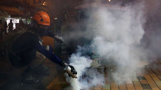 Policie v Hongkongu použila slzný plyn. Jeden z demonstrantů se snaží nádobu odhodit.