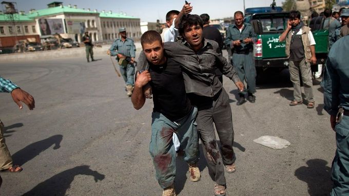 Afghánský policista pomáhá zraněnému muži dostat se dál od místa střelby. Centrum Kábulu, 18. června.