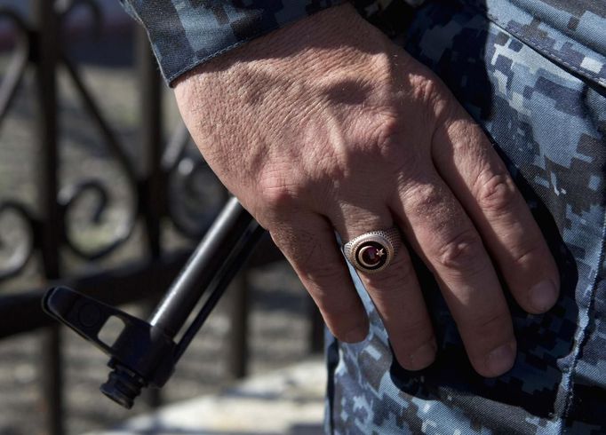 A policeman wears a ring showing the Islamic symbol of the star and crescent, as the barrel of a rifle is seen in the background, in the Chechen village of Itum-Kale April 29, 2013. The naming of two Chechens, Dzhokhar and Tamerlan Tsarnaev, as suspects in the Boston Marathon bombings has put Chechnya - the former site of a bloody separatist insurgency - back on the world's front pages. Chechnya appears almost miraculously reborn. The streets have been rebuilt. Walls riddled with bullet holes are long gone. New high rise buildings soar into the sky. Spotless playgrounds are packed with children. A giant marble mosque glimmers in the night. Yet, scratch the surface and the miracle is less impressive than it seems. Behind closed doors, people speak of a warped and oppressive place, run by a Kremlin-imposed leader through fear. Picture taken April 29, 2013. REUTERS/Maxim Shemetov (RUSSIA - Tags: SOCIETY POLITICS RELIGION) ATTENTION EDITORS: PICTURE 09 OF 40 FOR PACKAGE 'INSIDE MODERN CHECHNYA'. SEARCH 'REBUILDING CHECHNYA' FOR ALL IMAGES Published: Kvě. 1, 2013, 7:36 dop.