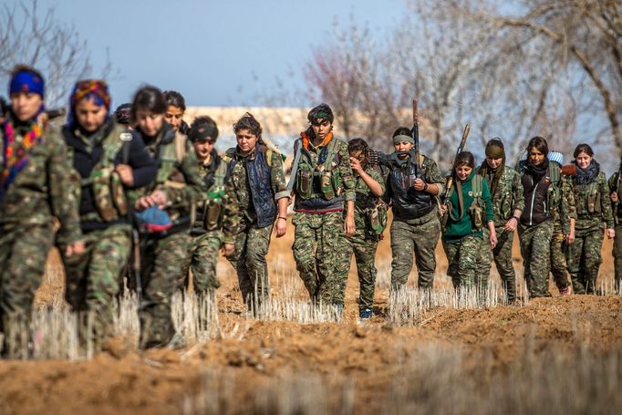 Female fighters of the Kurdish People's Protection Units (YPG) carry their weapons as they walk in the western countryside of Ras al-Ain