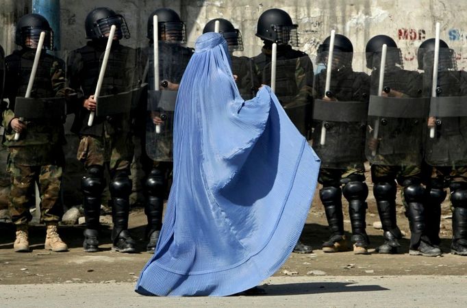 Pořádková policie u kábulského stadionu znepokojeně sleduje procházející ženu. 23. únor 2007.