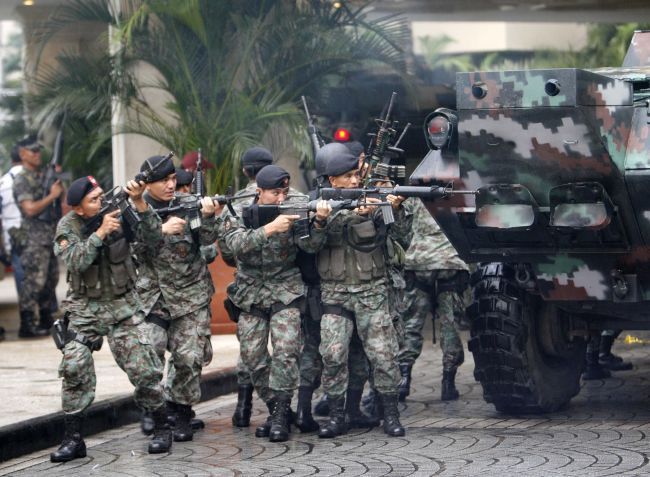 Vojáci se kryjí za obrněným transportérem