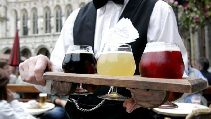 Bruselský číšník roznáší piva v barvách belgické vlajky.