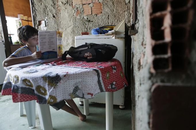 Gabriel Muniz, 11, does his homework at home in Campos dos Goytacazes, 274 kilometres (170 miles) northeast of Rio de Janeiro August 22, 2012. Despite being born with malformation of his feet, fourth grader Gabriel puts in hours into soccer everyday in his neighbourhood. He aspires to be a professional soccer player just like his idol Argentina's Lionel Messi of Barcelona FC. Picture taken on August 22. REUTERS/Ricardo Moraes (BRAZIL - Tags: SPORT SOCCER SOCIETY EDUCATION HEALTH) Published: Srp. 24, 2012, 2:25 dop.