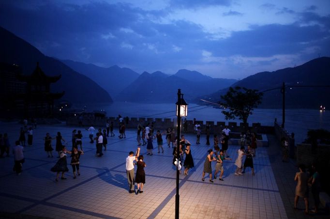 Residents dance at a square next to the Yangtze River in Badong city, 100km (62 miles) from the Three Gorges dam in Hubei province in this August 8, 2012 file photo. China relocated 1.3 million people during the 17 years it took to complete the Three Gorges dam. Even after finishing the $59 billion project last month, the threat of landslides along the dam's banks will force tens of thousands to move again. It's a reminder of the social and environmental challenges that have dogged the world's largest hydroelectric project. While there has been little protest among residents who will be relocated a second time, the environmental fallout over other big investments in China has become a hot-button issue ahead of a leadership transition this year. Picture taken on August 8, 2012. To match story CHINA-THREEGORGES/ REUTERS/Carlos Barria/Files (CHINA - Tags: POLITICS ENVIRONMENT BUSINESS ENERGY TPX IMAGES OF THE DAY) Published: Srp. 22, 2012, 8:36 odp.