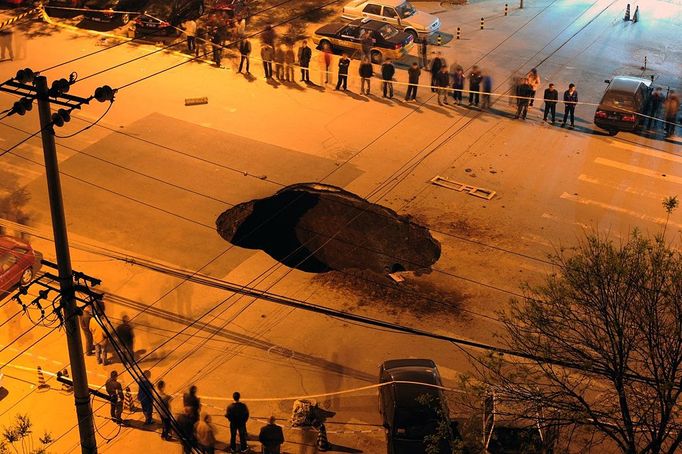 Workers block off the site of a sinkhole which occured overnight on Shiliuzhuang road, in Beijing on April 26, 2011. A section of the road collapsed beneath a truck, slightly injuring the driver and a passenger, who both jumped out the vehicle beforeit sank into the hole, as an authoritiy suspects the hole was caused by the construction of a subway line. CHINA OUT AFP PHOTO