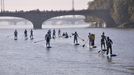 Paddleboarding. Tito vodáci plují na prknech, která jsou podobná těm, co mívají surfaři. Vpřed se pohybují pomocí dlouhého pádlä, aby dosáhli do vody ze stoje.