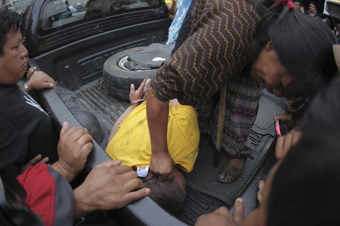 A woman pulls a man's hair in Tactic, in Alta Verapaz region, some 189km (117 miles) from Guatemala City, September 13, 2012. The local community tied up and beat four men who were accused of theft in the aftermath of a school killing, which had occurred on Wednesday. The man, who had entered a classroom and killed two children, ages 8 and 13, with a machete, was lynched and burnt alive by a mob, local media reported. REUTERS/Jorge Dan Lopez (GUATEMALA - Tags: CRIME LAW SOCIETY) Published: Zář. 13, 2012, 6:18 odp.