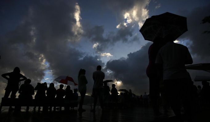 Rain showers fall as tourists look at a cloudy sky as a full solar eclipse begins in the northern Australian city of Cairns November 14, 2012. REUTERS/Tim Wimborne (AUSTRALIA - Tags: SOCIETY ENVIRONMENT) Published: Lis. 13, 2012, 9:35 odp.