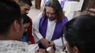 Catholic priest Adolfo Huerta (C), known as "Gofo", baptizes a young boy at the church "Our Lord of Mercy" in the El Toreo neighbourhood in Saltillo February 24, 2013. Ordained five years ago, Huerta is an unconventional priest who likes rock music, dyes the ends of his hair red, dresses in black, and enjoys riding his motorcycle. Huerta found God and priesthood while studying philosophy at the Pontifical University in Mexico City and working with HIV-positive patients and sex workers as a social activist. He says it is important to demystify faith and accept people's differences without judgment, and in his sermons he references rock songs, quotes books and tells jokes. Picture taken February 24, 2013. REUTERS/Daniel Becerril (MEXICO - Tags: RELIGION SOCIETY) ATTENTION EDITORS: PICTURE 3 OF 26 FOR PACKAGE 'CHURCH, FAITH AND ROCK'N ROLL' SEARCH 'PRIEST DANIEL' FOR ALL IMAGES Published: Bře. 15, 2013, 10:22 dop.