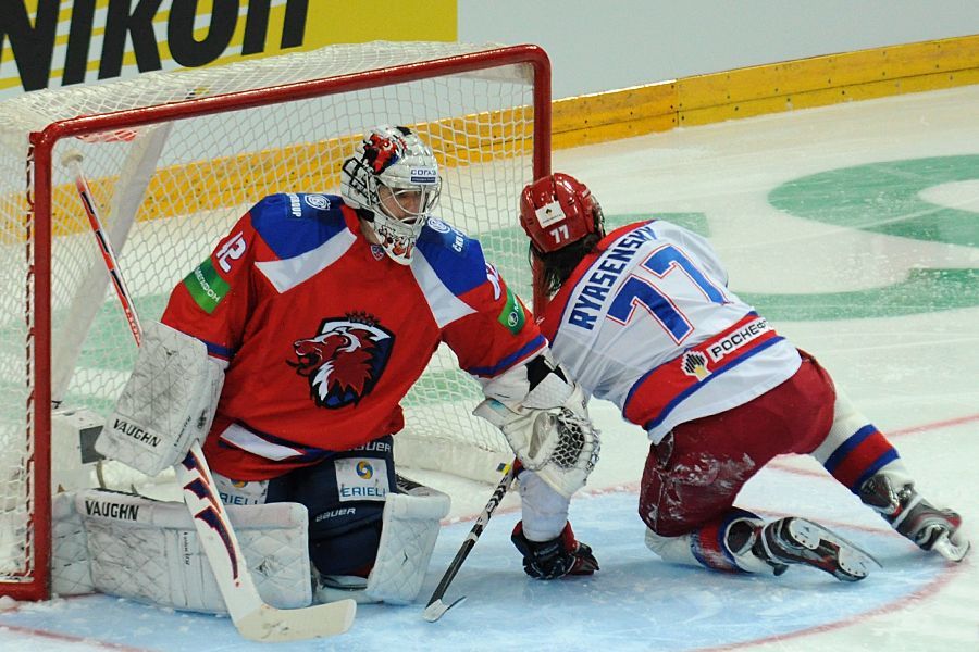 Hokejový brankář Lva Praha Tomáš Pöpperle chytá střelu Jevgenije Rjazanceva v utkání KHL proti CSKA Moskva.