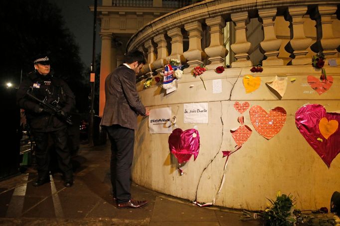 Před francouzskou ambasádou v Londýně. Ozbrojený policista sleduje, jak muslim upevňuje na pietní místo za Charlie Hebdo ceduli s nápisem "Ne mým jménem".