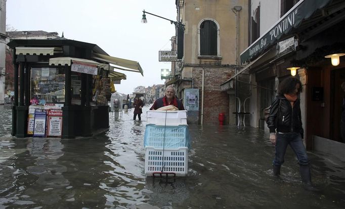 A worker transports materials during a period of seasonal high water in Venice October 27, 2012. The water level in the canal city rose to 127 cm (50 inches) above the normal level, according to the monitoring institute. REUTERS/Manuel Silvestri (ITALY - Tags: ENVIRONMENT SOCIETY TRAVEL) Published: Říj. 27, 2012, 12:15 odp.